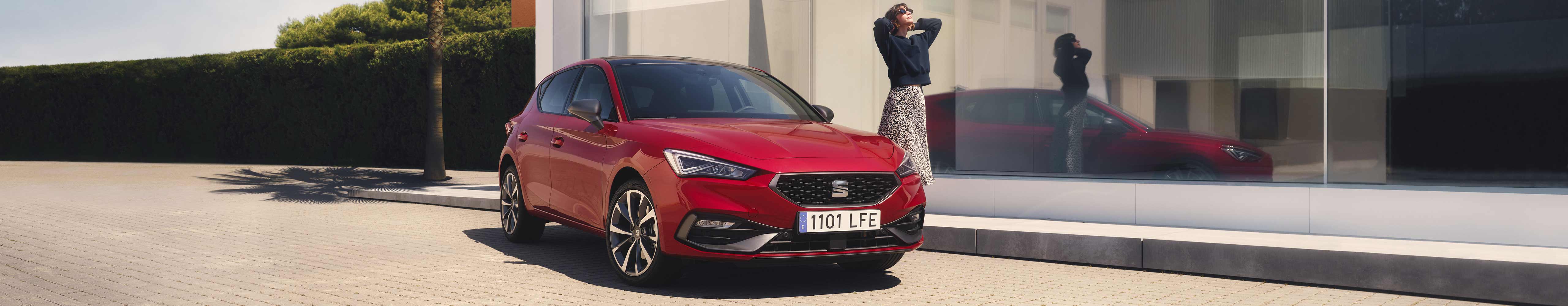 Woman standing next to SEAT Leon desire red colour