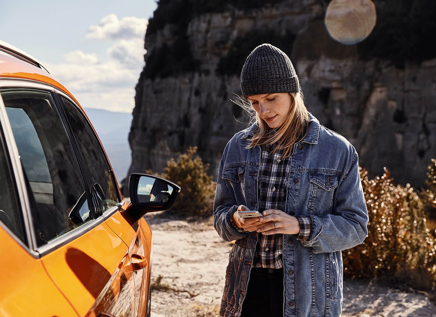 SEAT new car services and maintenance – Woman on a phone standing beside a parked SEAT Ateca SUV