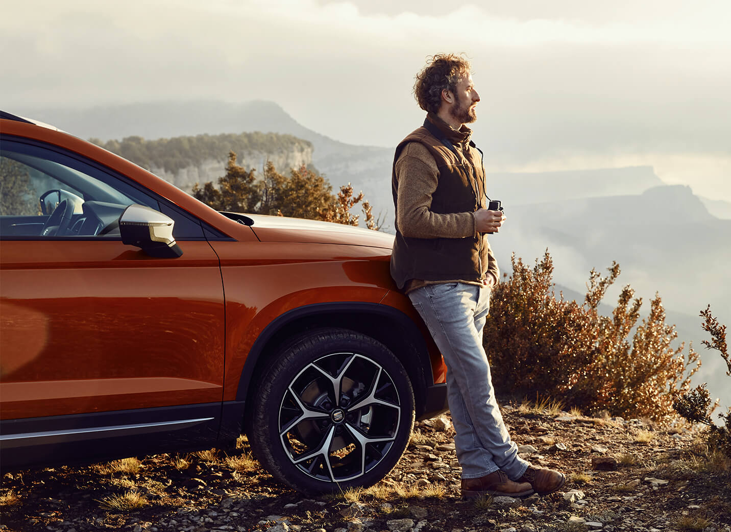 SEAT new car services and maintenance – SEAT Arona crossover SUV parked overlooking a valey with man leaning on the car